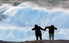 Dos turistas observan el oleaje en la cosa de Muxía, este miércoles en A Coruña