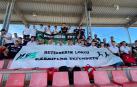 Los componentes de Hiru Herri posan con una pancarta de apoyo en la grada del estadio de Gijón