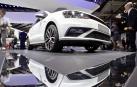 Varias personas alrededor de un coche en una exposición de una feria del automóvil.