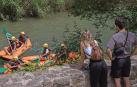Una pareja observa varios kayaks descendiendo por el Ega