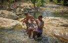 Dos jóvenes se refrescan en el río Arga a su paso por Huarte