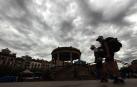 Dos turistas pasean por la Plaza del Castillo de Pamplona con un cielo tormentoso este jueves