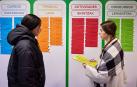 Dos corresponsales juveniles de una edición anterior realizan labores ante una tabla de actividades