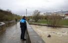 Un policía municipal de Burlada observando la crecida del río Arga