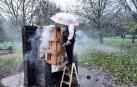 Christian Constantin se protege con un paraguas de la lluvia y echa agua sobre la chimenea artesal que se construyó en un merendero de Huarte
