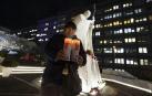 Una mujer sujeta dos velas con la imagen del papa Francisco ante el hospital Gemelli de Roma donde está hospitalizado /