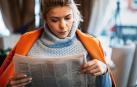 Una mujer, leyendo el periódico en una cafetería
