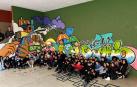 El alumnado de 3º de la ESO con el mural pintado en un rincón del patio con el que invita a reflexionar sobre las compras