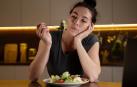 Una chica mira su ensalada sin ganas de comer
