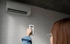 Una mujer, regulando el aire acondicionado de su vivienda
