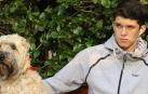Un adolescente sentado en un banco con su perro mientras lo acaricia