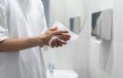 Una persona secándose las manos con una toallita de papel en un baño