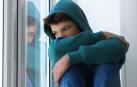 Un adolescente pensativo mirando por la ventana