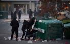 Cuatro manifestantes se protegen detrás de un contenedor volcado junto a la rotonda de la avenida Barañáin con calle Ermitagaña